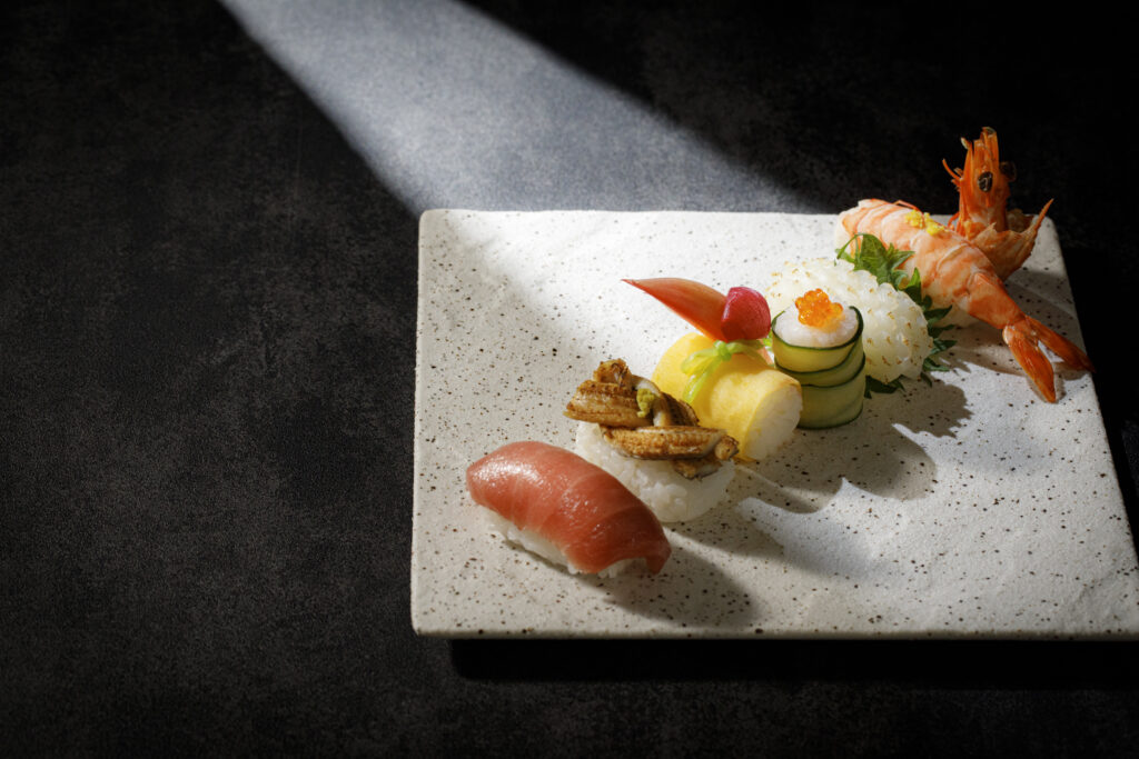 名古屋市の結婚式場ビアンカーラヒルサイドテラスの、マグロや海老、穴子が並ぶ握り寿司の盛り合わせ。一筋の光が鮮やかなネタを照らす和の婚礼料理。