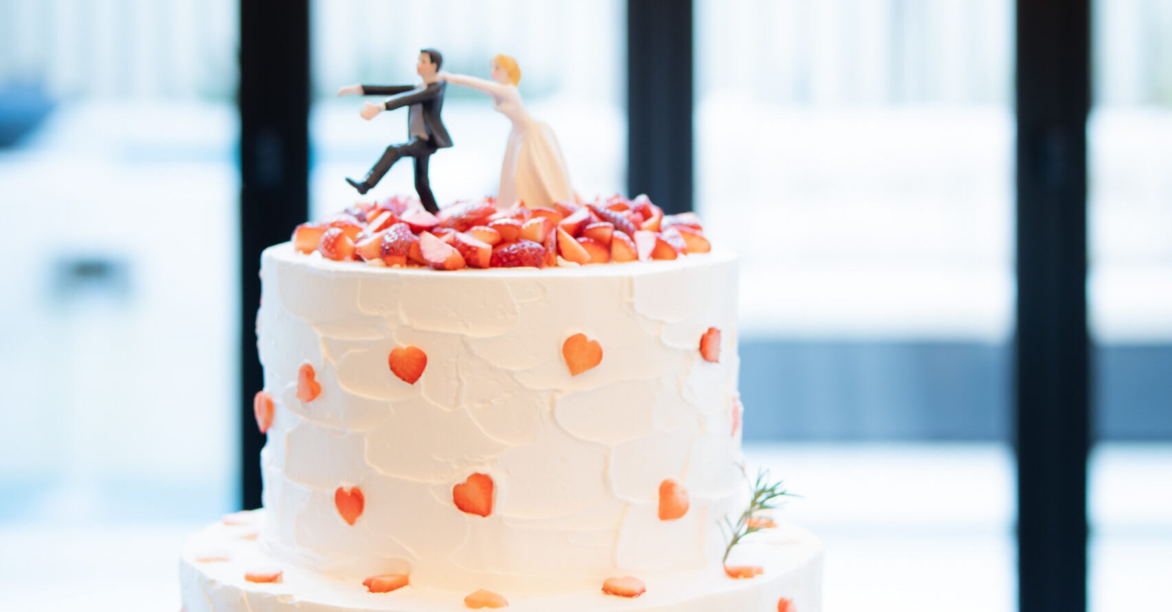 【名古屋市結婚式場ビアンカーラテラス】たっぷりのイチゴとハートのデザインが施された、ユニークなケーキトッパーが目を引くウェディングケーキ。名古屋市にある市の中心部で叶える、お二人らしさを表現したオリジナル生ケーキは、名古屋市内での披露宴を盛り上げる人気の演出として、ゲストの笑顔を誘う瞬間を詳細に描写しています。