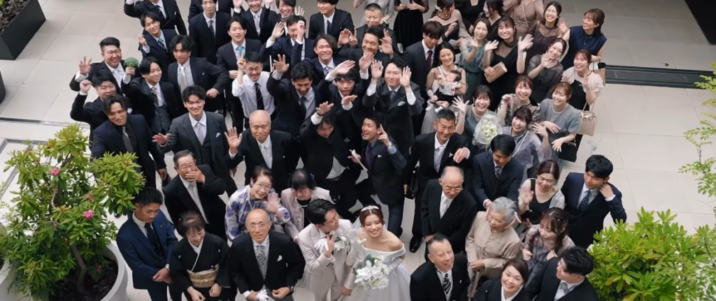 【名古屋市結婚式場ビアンカーラテラス】開放的なテラスに集まった親族や友人の皆様が、笑顔で手を振る一体感あふれる集合写真。名古屋市にある市の喧騒を忘れるような広々とした空間で、名古屋市内外から集まった大切なゲスト全員と思い出を共有できる、当館ならではの賑やかで感動的な場面です。