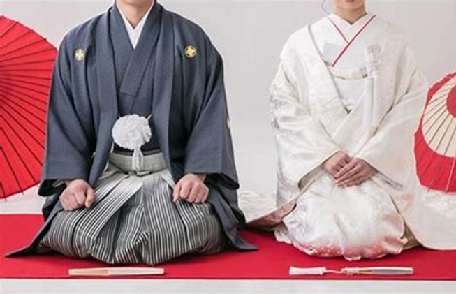 【名古屋市結婚式場ビアンカーラテラス】にて、赤い毛氈の上で凛と正座し、新たな門出のご挨拶をする新郎新婦様。名古屋市にある市の式場で叶える、伝統的な紋付袴と美しい白無垢姿による和装のしつらえは、名古屋市内での結婚式を控えたお二人の誠実な決意と感謝の心を詳細に描写しています。