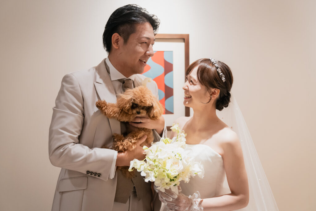 名古屋市の結婚式場ビアンカーラヒルサイドテラス。愛犬を抱く新郎と微笑む新婦の心温まる対面シーン。ペットも家族として参加できる貸切感ある挙式演出。