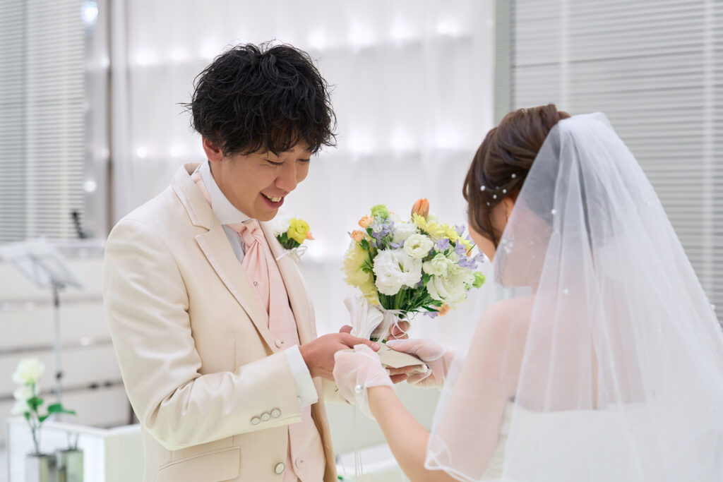 名古屋市の結婚式場ビアンカーラヒルサイドテラス。挙式で新郎から新婦へブーケを贈る感動の演出。幸せな笑顔で誓いを交わす、純白のドレス姿の新郎新婦。