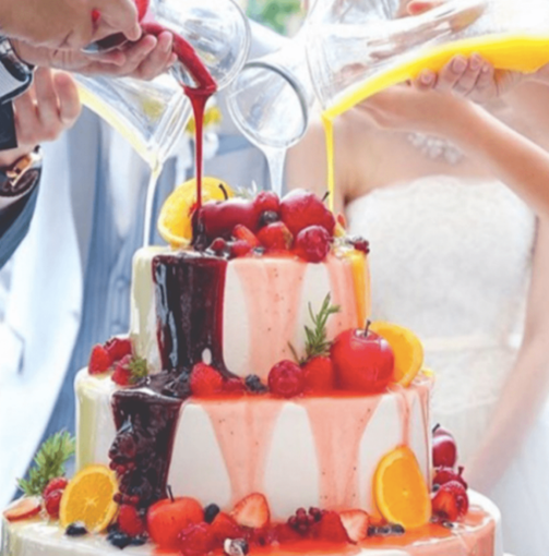 名古屋市結婚式場ビアンカーラテラスのイチゴや姫リンゴがふんだんに飾られた3段のウェディングケーキに、3つのピッチャーから異なる色のソースを同時に注ぎ完成させる演出。