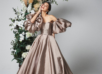 結婚式場ビアンカーラヒルサイドテラス。モダンな空間に映える、光沢感のあるブロンズのカラードレスと、ボリュームのあるパフスリーブが洗練された花嫁。