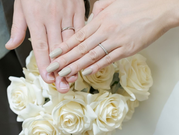 名古屋市の結婚式場ビアンカーラヒルサイドテラスのチャペルで誓い合う、新郎新婦の手元をクローズアップ。白いバラのブーケを背景に、薬指に輝く結婚指輪が永遠の愛を象徴しています。