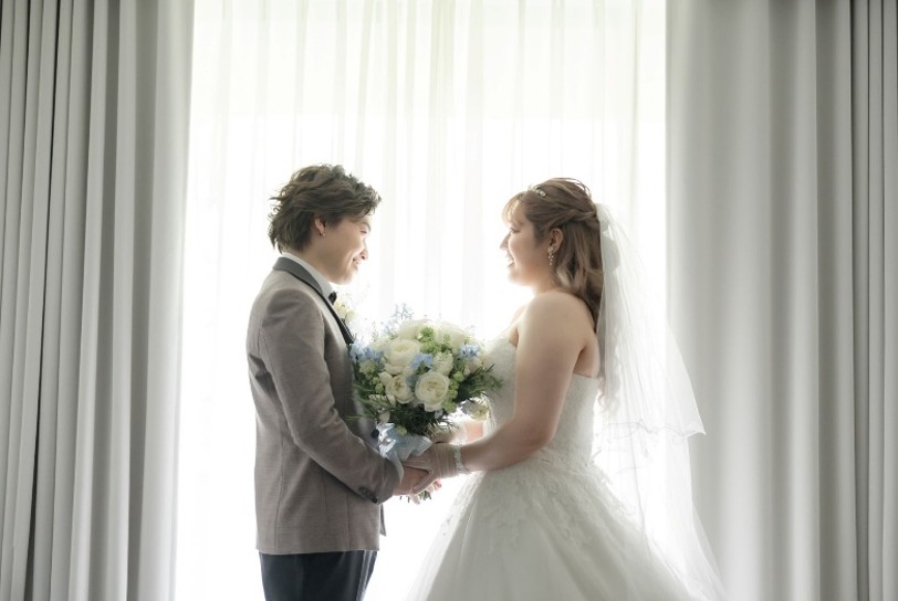 名古屋市の結婚式場ビアンカーラヒルサイドテラス。柔らかな自然光が差し込む中、見つめ合う新郎新婦。白を基調とした上質な空間で叶うアーバンリゾート挙式。