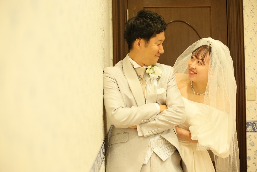 名古屋市の結婚式場ビアンカーラヒルサイドテラスで、結婚式当日の幸せな瞬間を振り返りながら、照れくさそうに見つめ合うタキシード姿の新郎とウェディングドレス姿の新婦。